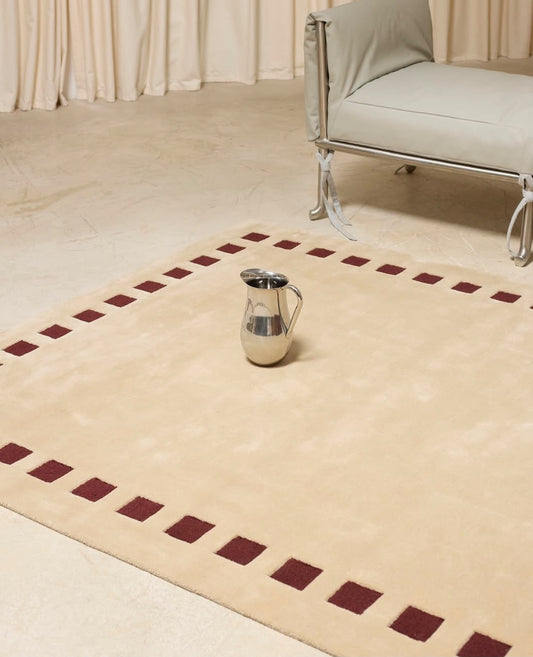 Cream and burgundy geometric hand tufted rug with minimalist dashed border styled in a modern interior
